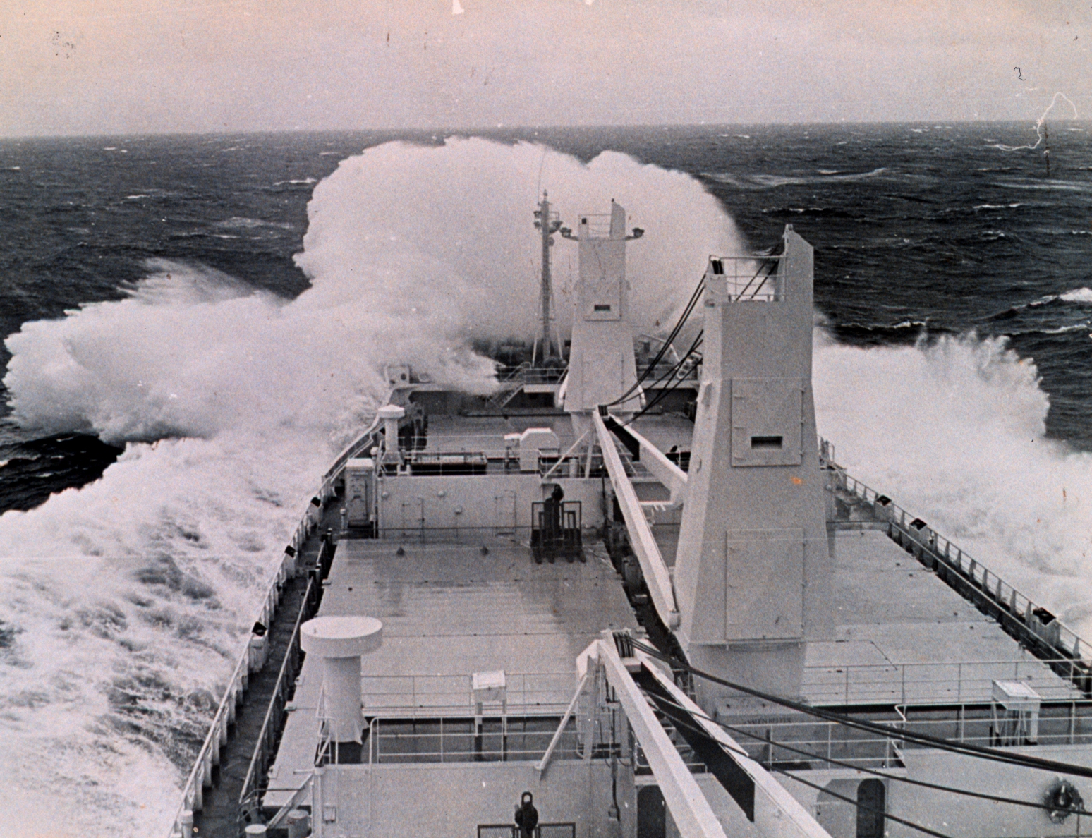 A merchant ship driving into heavy seas, water breaking over its bow